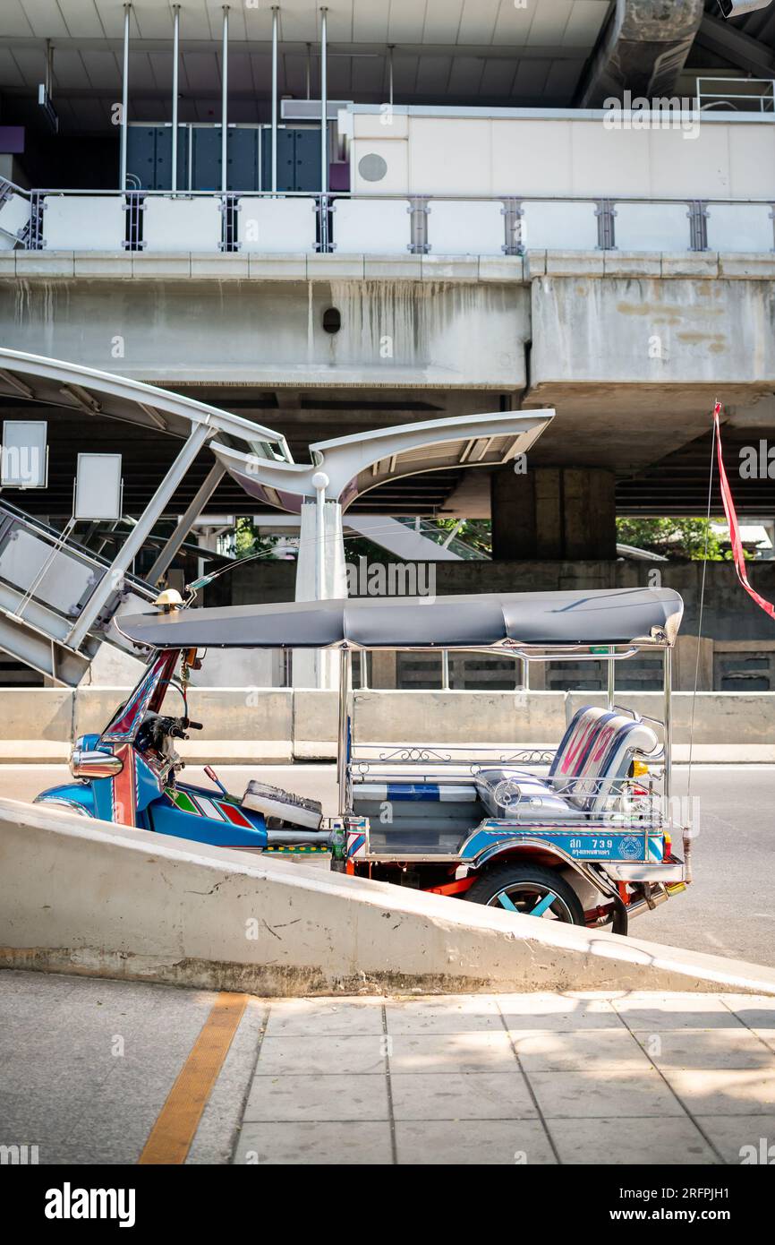 Un tuk tuk thaï classique attend devant la station aérienne de Chong Nonsi BTS dans le quartier de Chong Nonsi à Bangkok, en Thaïlande. Banque D'Images