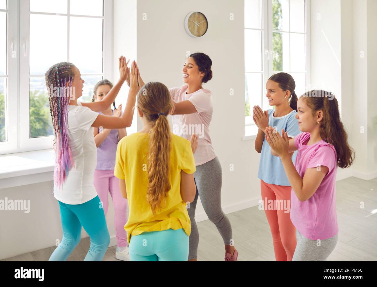 Chorégraphe sympathique féminin donnant High Five à ses élèves filles dans le studio de danse. Banque D'Images