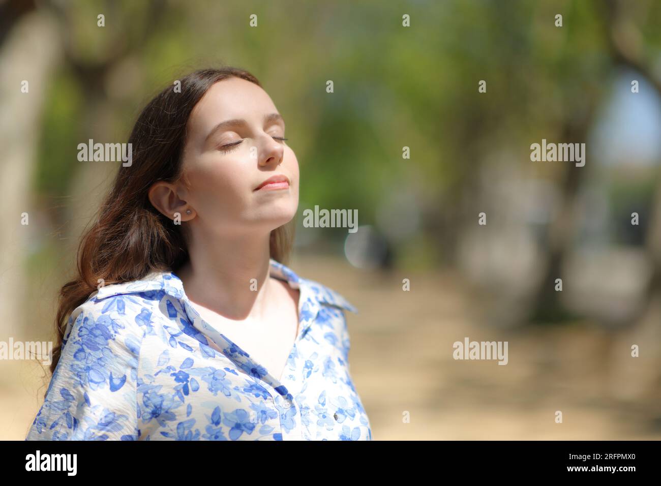 Femme respirant de l'air frais debout une journée ensoleillée dans la nature Banque D'Images