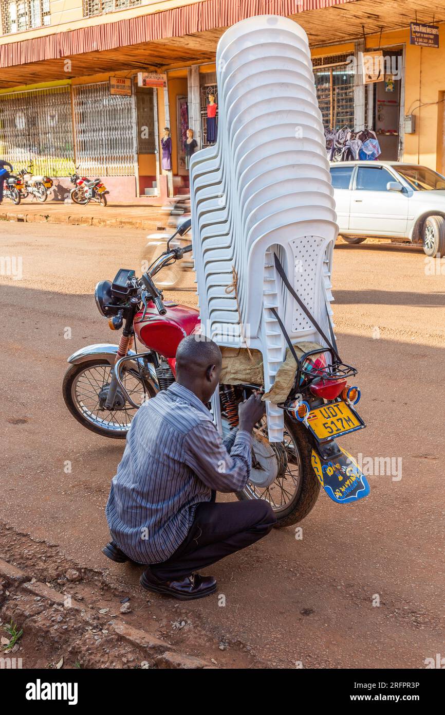 chauffeur de boda-boda sécurisant une pile de chaises sur sa moto. Banque D'Images