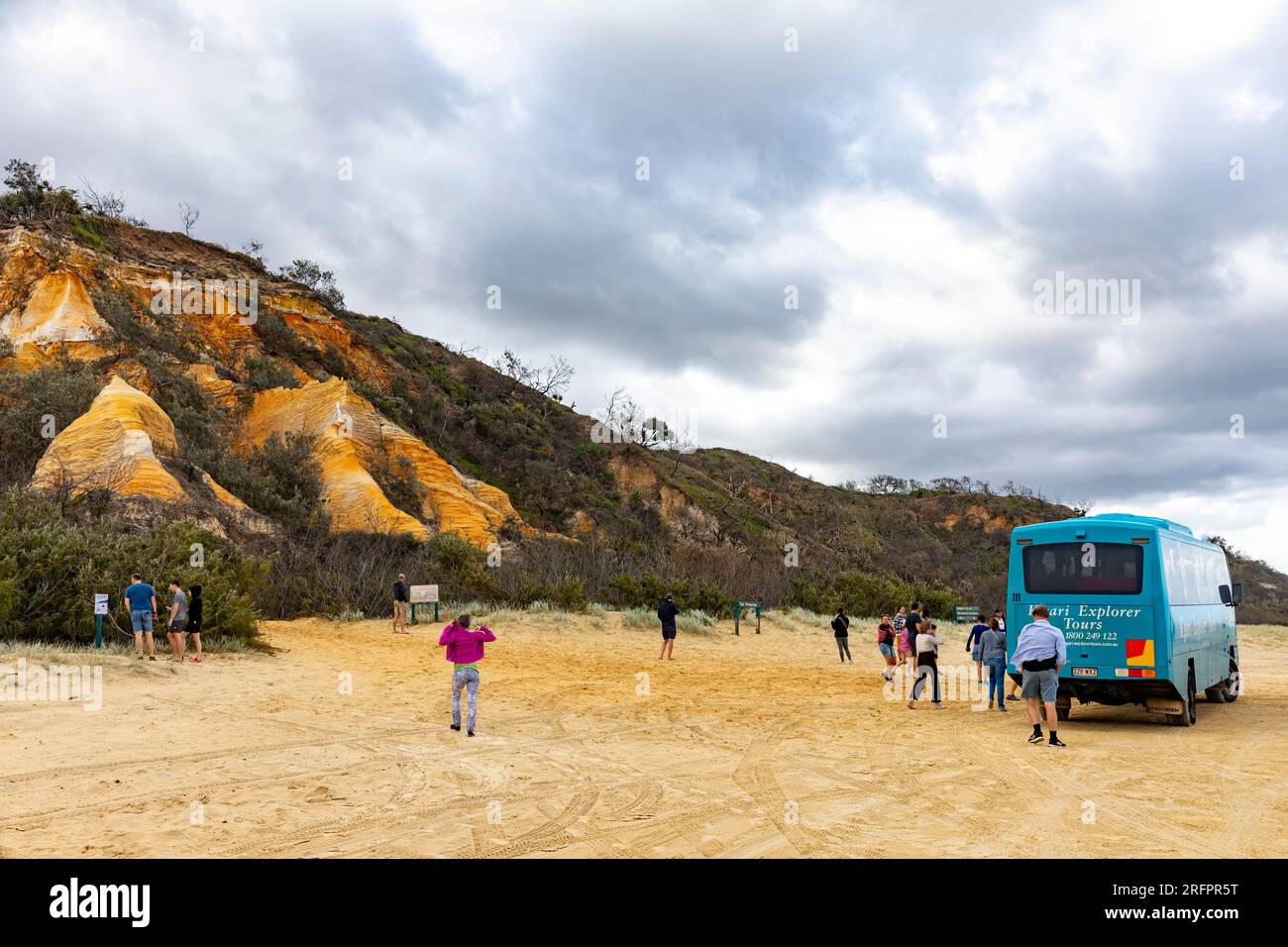 Fraser Island K'gari, bus touristique explorateur sur la plage de 75 miles aux Pinnacles alors que les touristes regardaient les sables colorés, Queensland, Australie Banque D'Images