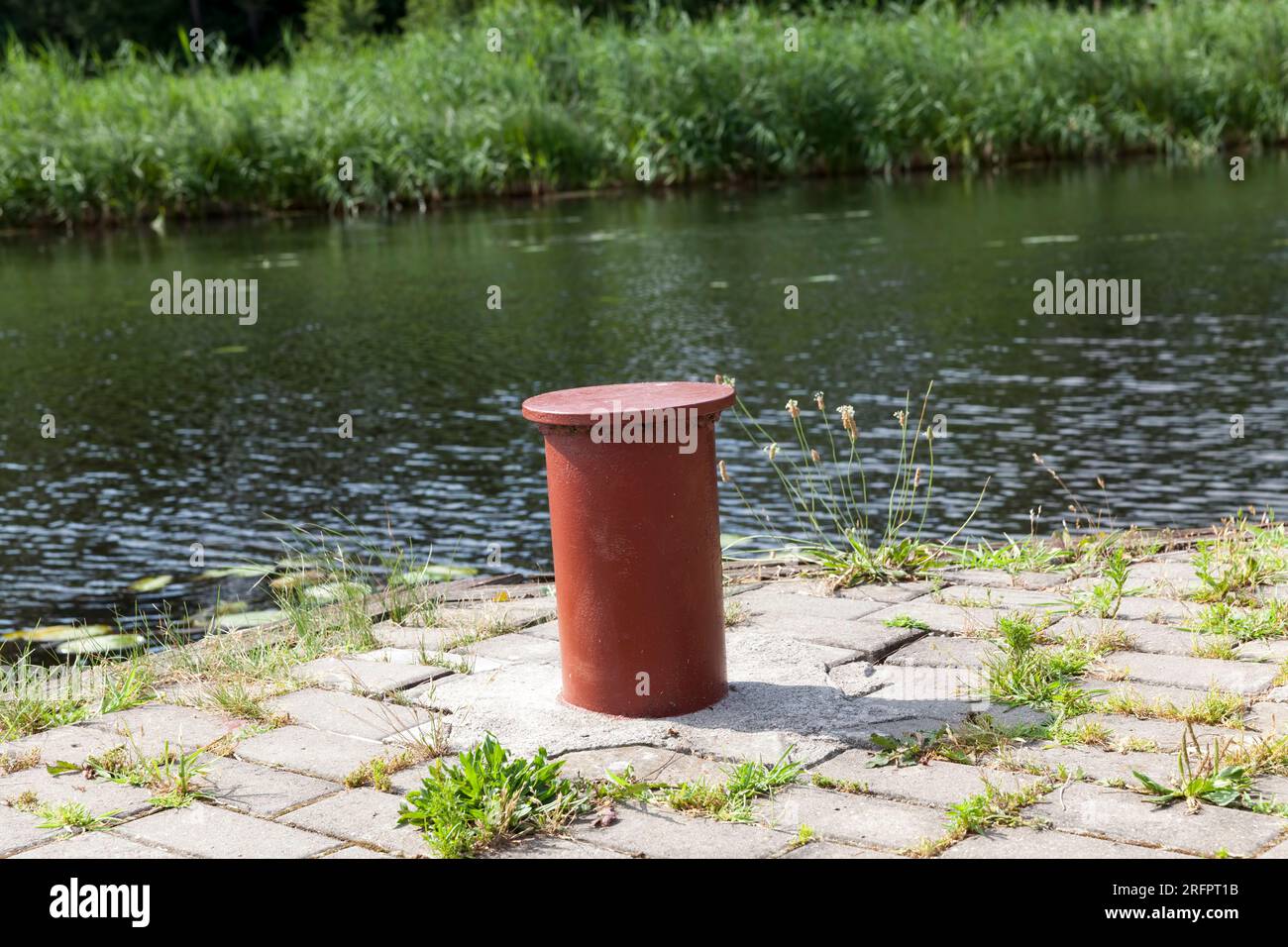 Fixation métallique pour amarrer les bateaux et les navires à la jetée près du lac, un poteau métallique rouge (Bollards) pour attirer l'attention Banque D'Images