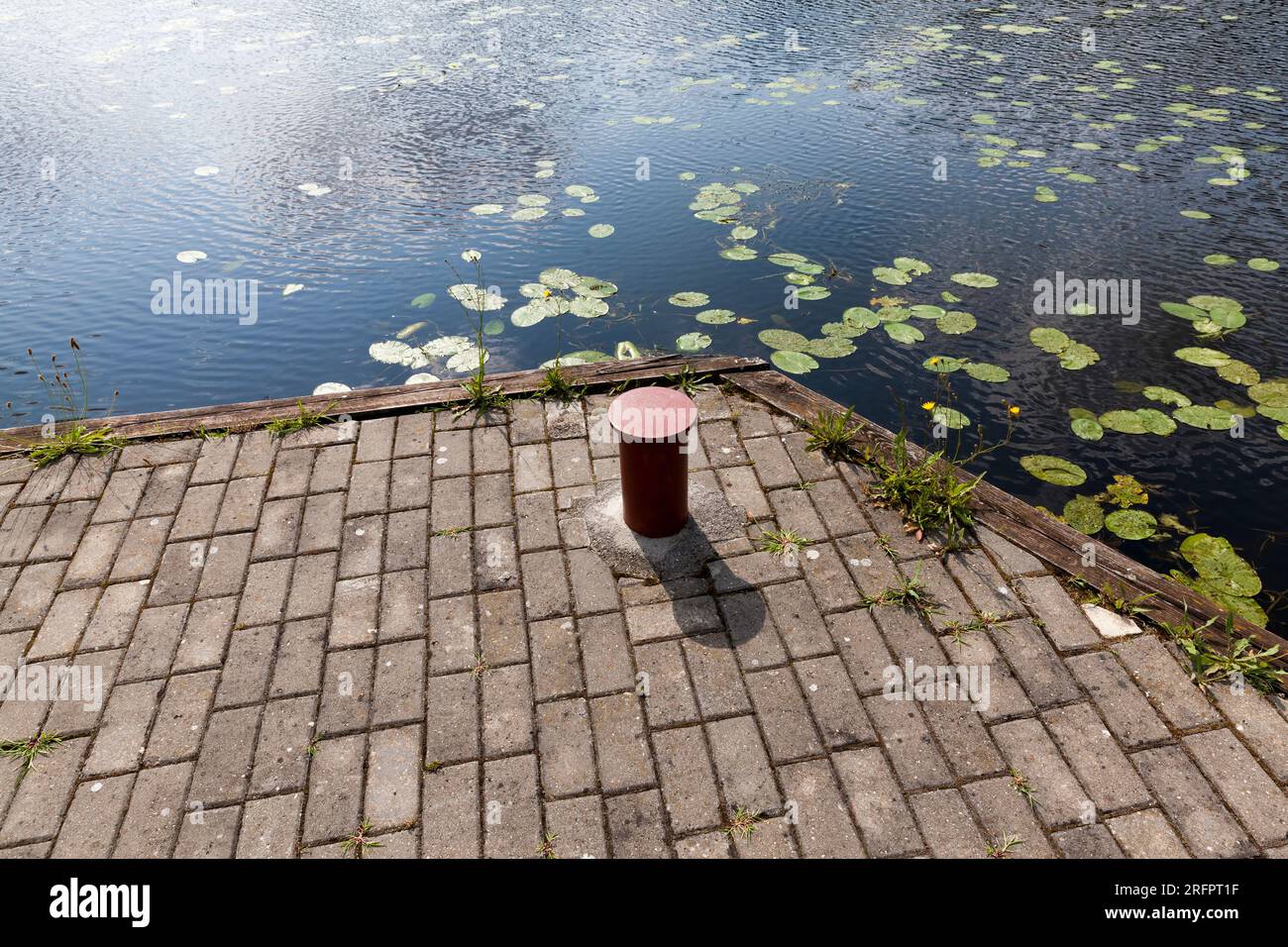 Fixation métallique pour amarrer les bateaux et les navires à la jetée près du lac, un poteau métallique rouge (Bollards) pour attirer l'attention Banque D'Images