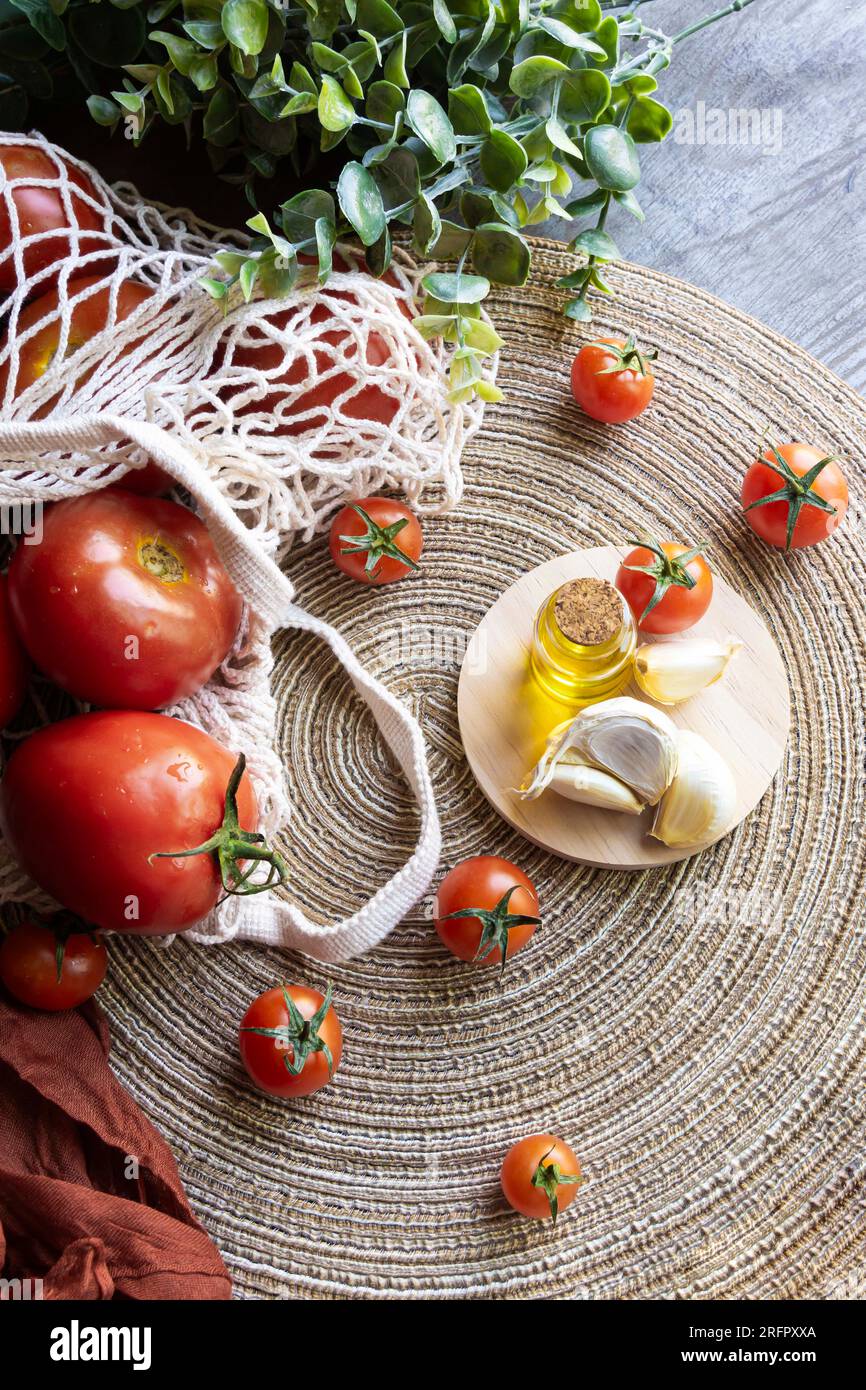 Produits méditerranéens. Tomates rouges dans un sac à provisions durable, une bouteille d'huile d'olive extra vierge et quelques grenades. Banque D'Images