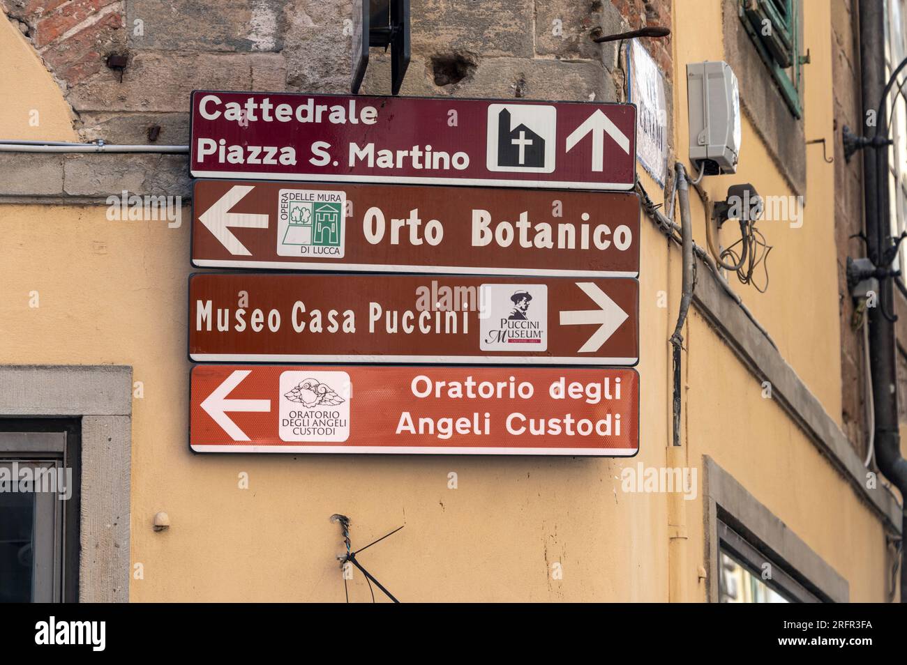 Un signe touristique brun des attractions touristiques à proximité sur un mur dans l'une des principales rues commerçantes de la ville de Lucca, région Toscane, Toscane, Italie, Banque D'Images