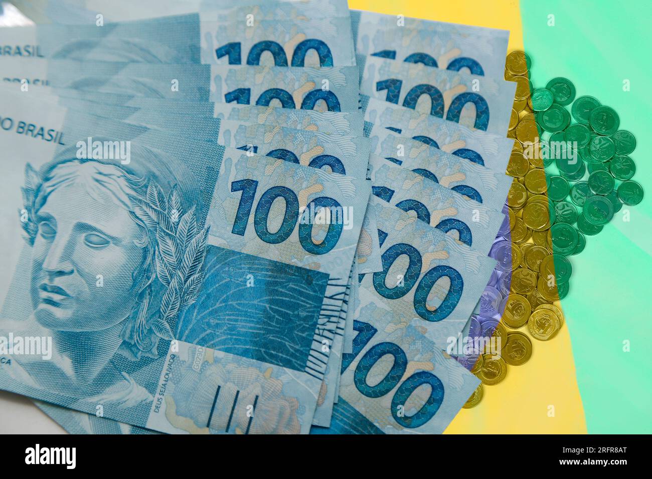 Plusieurs centaines de reais billets et pièces de monnaie du Brésil sur fond de couleurs brésiliennes - concept d'argent Banque D'Images
