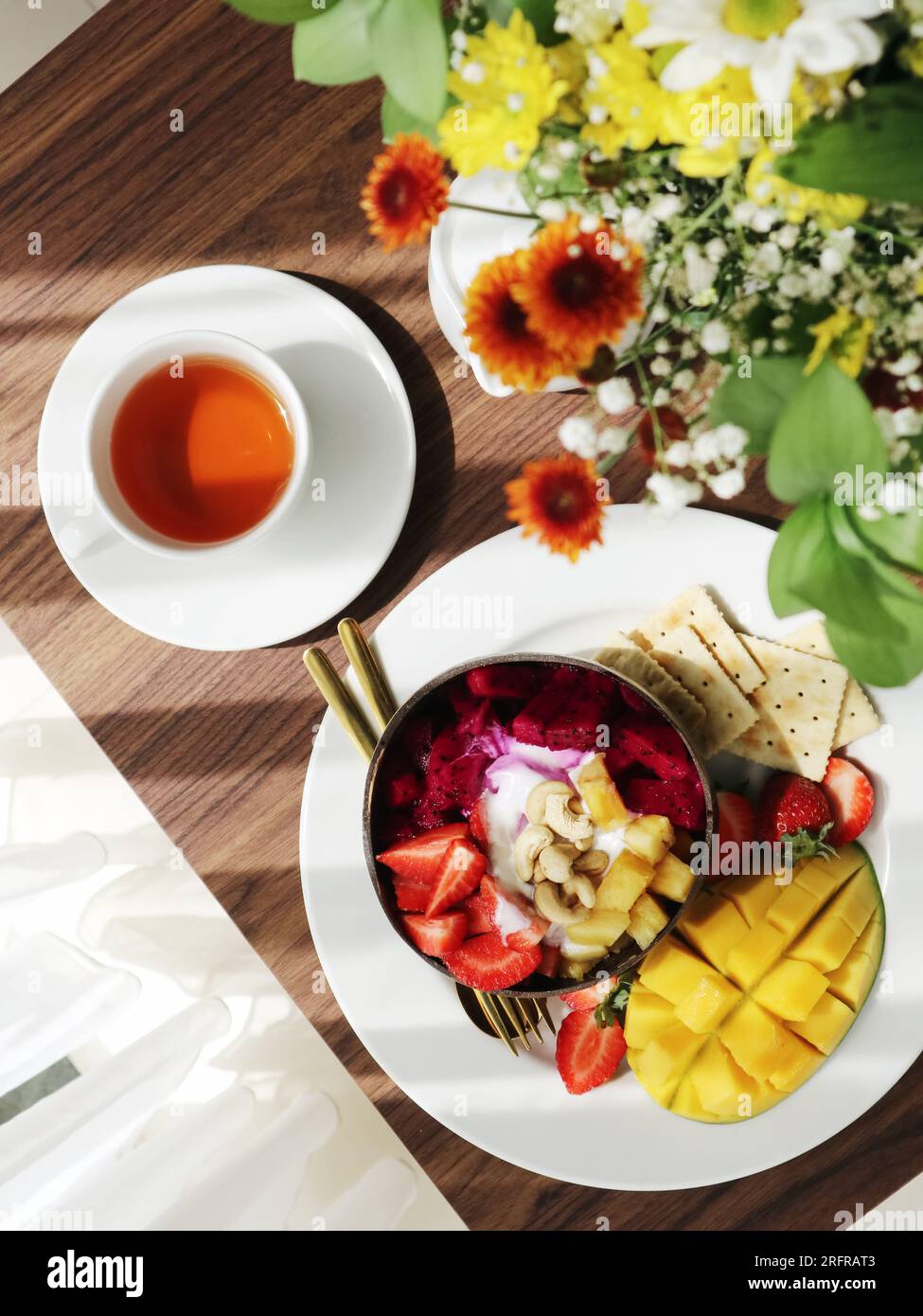 Bol à smoothie avec mangue, fraise, fruit du dragon et noix de cajou dans le bol de noix de coco gros plan Banque D'Images
