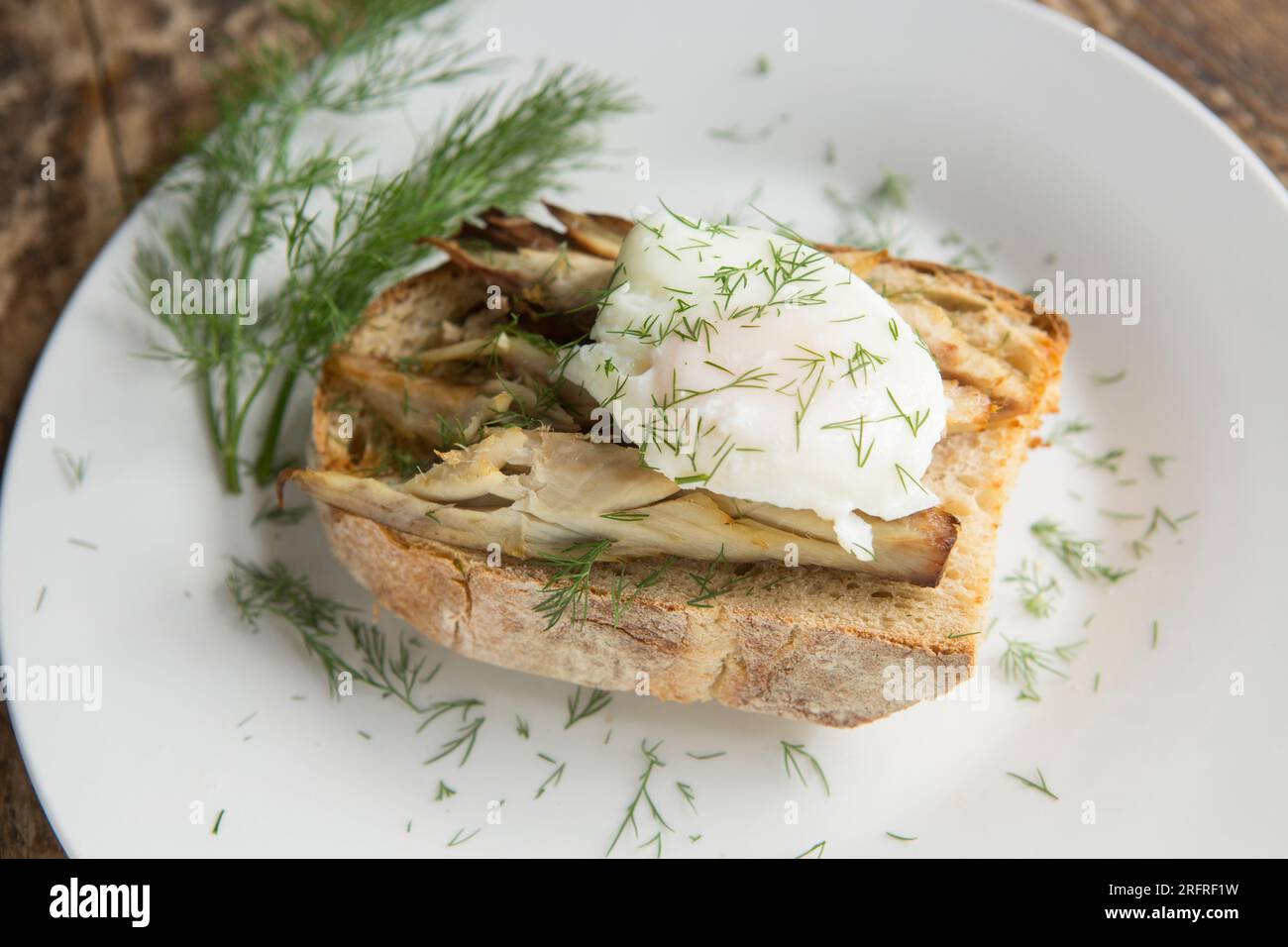 Maquereau fumé chaud, Scomber scombrus, servi sur du pain au levain beurré et grillé avec un œuf poché et garni d'aneth. Angleterre Royaume-Uni GB Banque D'Images