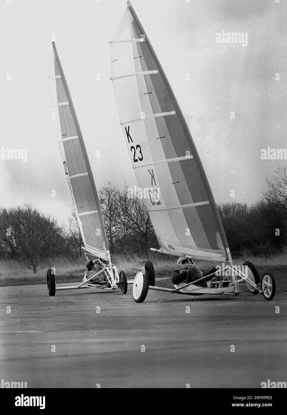1987, deux concurrents dans un événement de yatching terrestre, Angleterre, Royaume-Uni. Aussi connu sous le nom de voile terrestre, il consiste à utiliser une voile pour la poudre à vent similaire à celle utilisée pour naviguer sur l'eau, mais en utilisant des roues. Banque D'Images