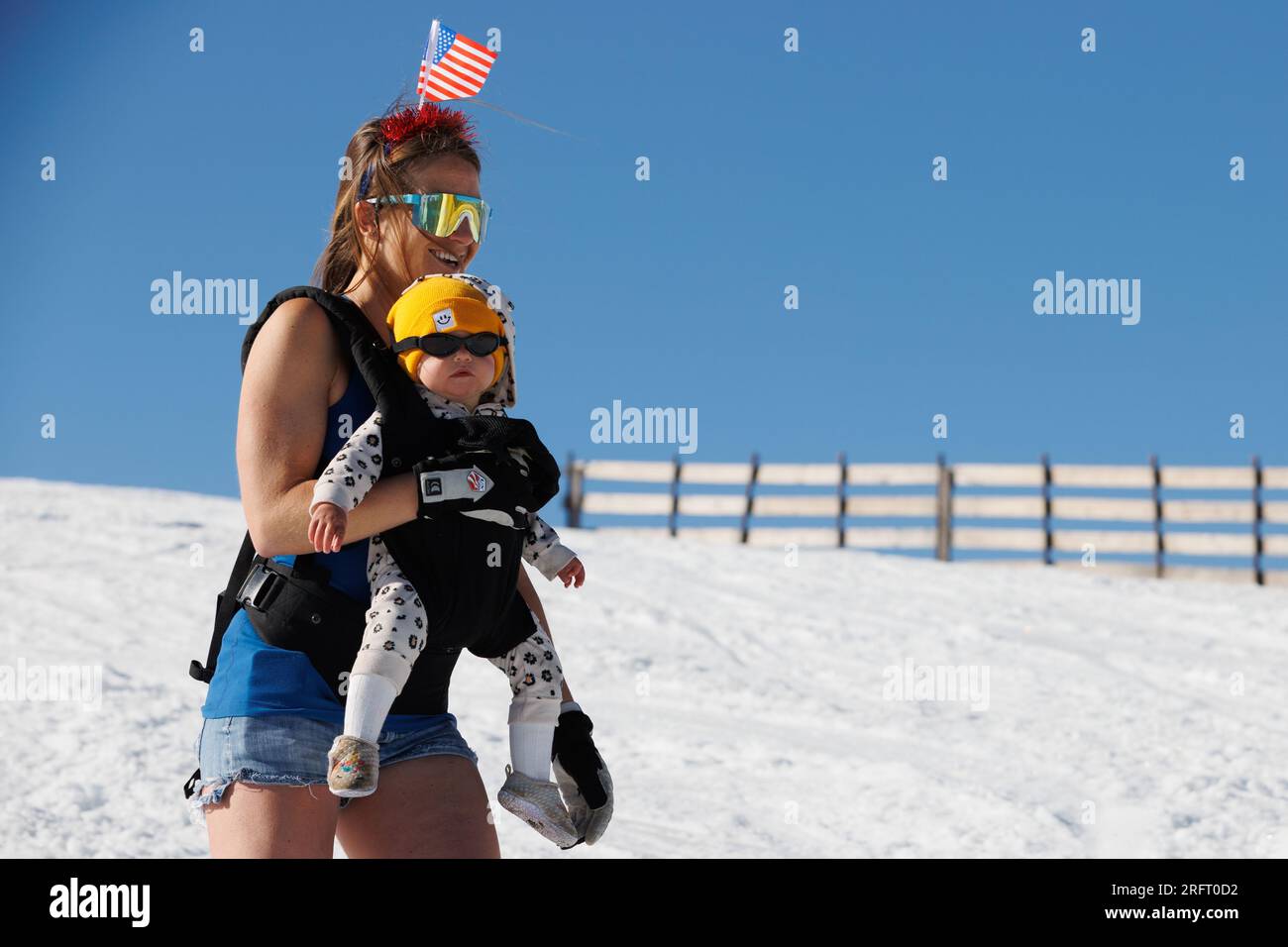 Mammoth Lakes, Californie. 4 juillet 2023. Une femme skie avec un bébé et un drapeau américain sur la tête à Mammoth Mountain ski Resort par une journée d'été claire. Banque D'Images