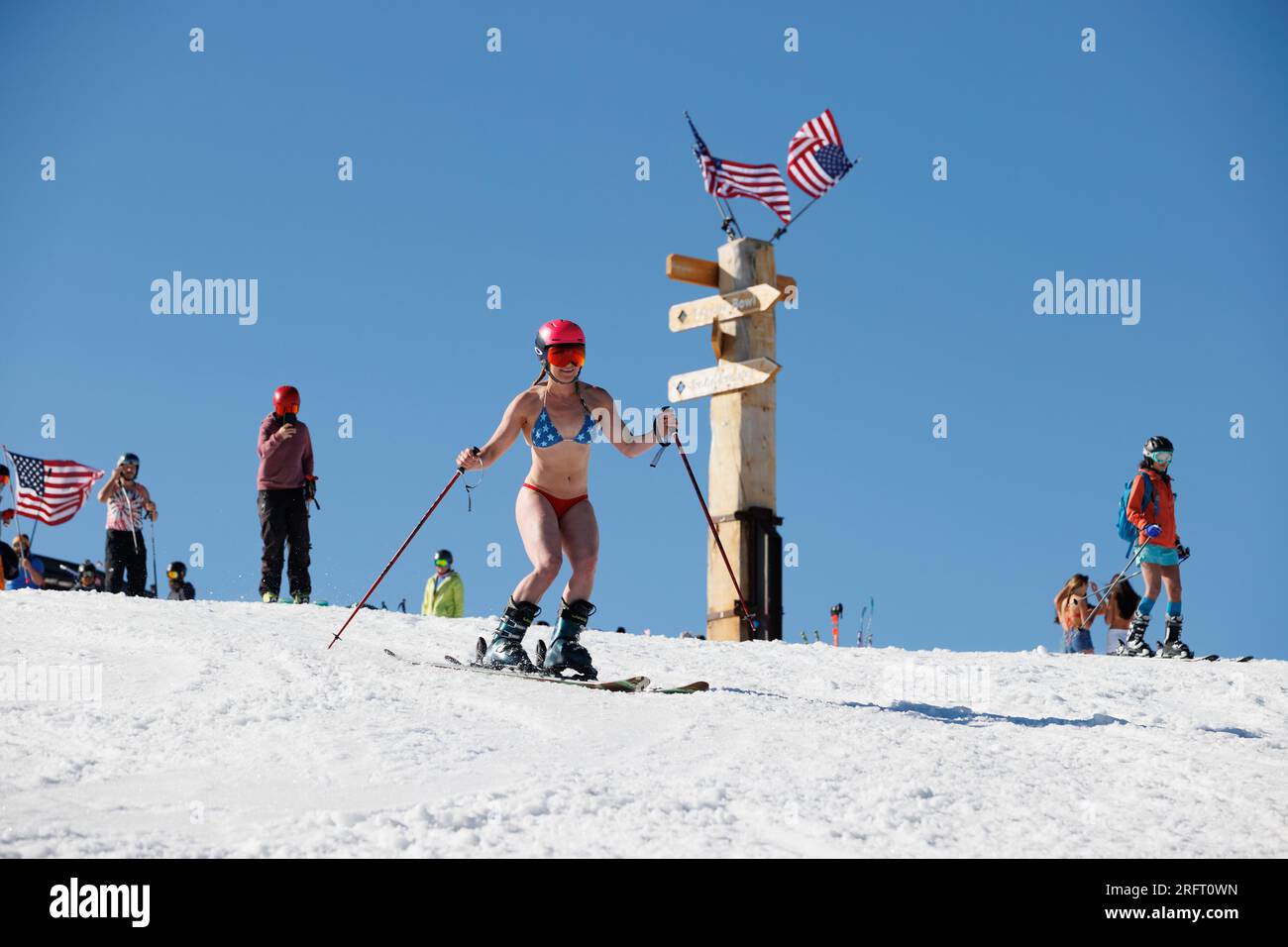 Mammoth Lakes, Californie. 4 juillet 2023. Une femme en forme en bikini et casque ski devant les drapeaux américains à Mammoth Mountain ski Resort par une journée d'été claire. Banque D'Images