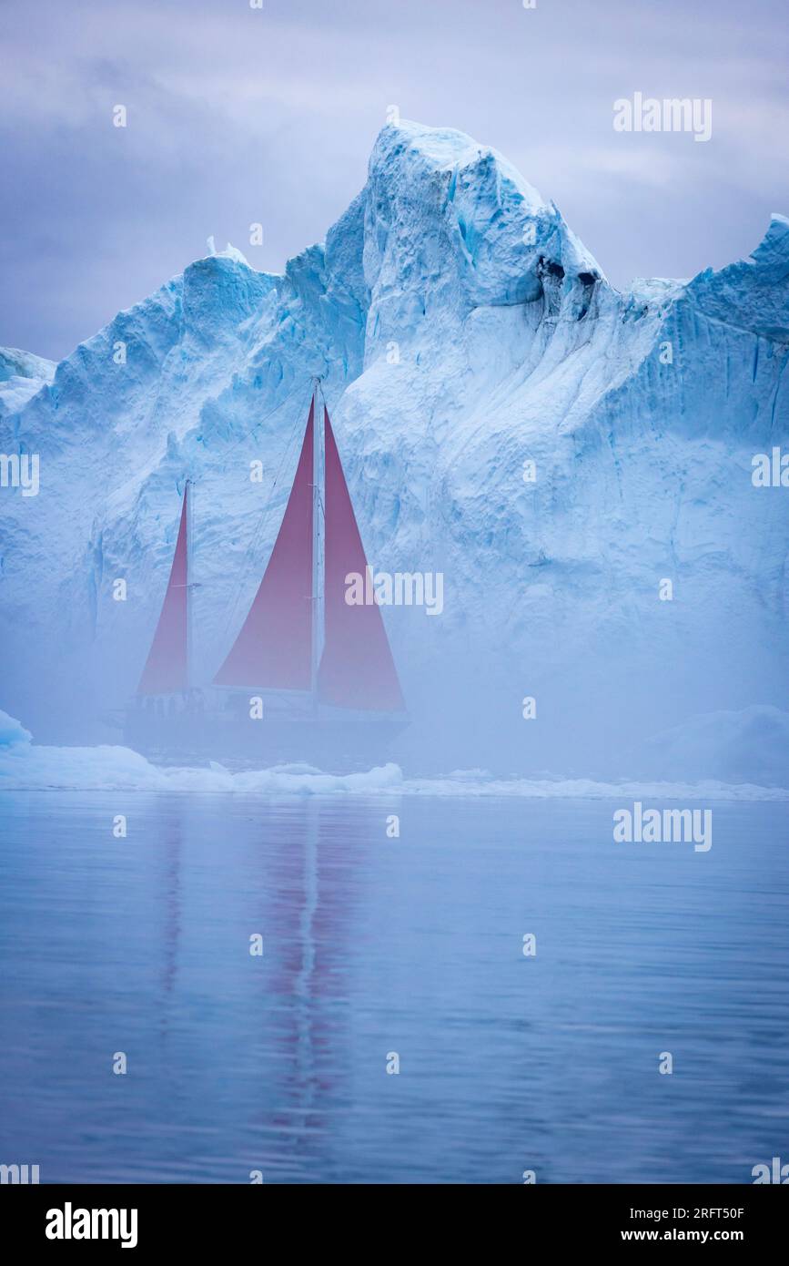 Des voiles rouges longent le fjord de glace d'Ilulissat au nord du cercle polaire arctique, dans la baie de Disko, au Groenland Banque D'Images