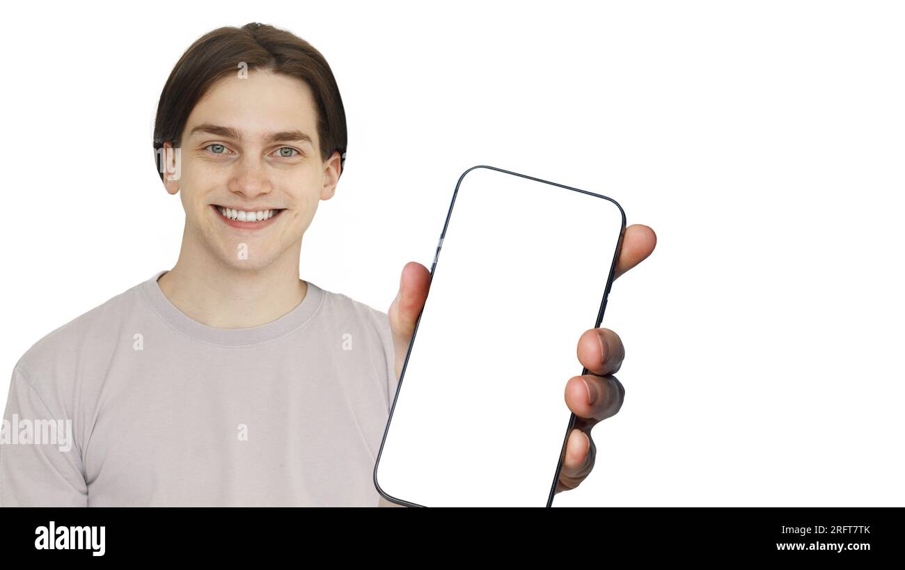 Jeune homme adulte souriant tenant le grand téléphone cellulaire vide avec l'affichage d'écran blanc vide. Heureux gars avec smartphone recommandant une nouvelle application ou mobile Banque D'Images