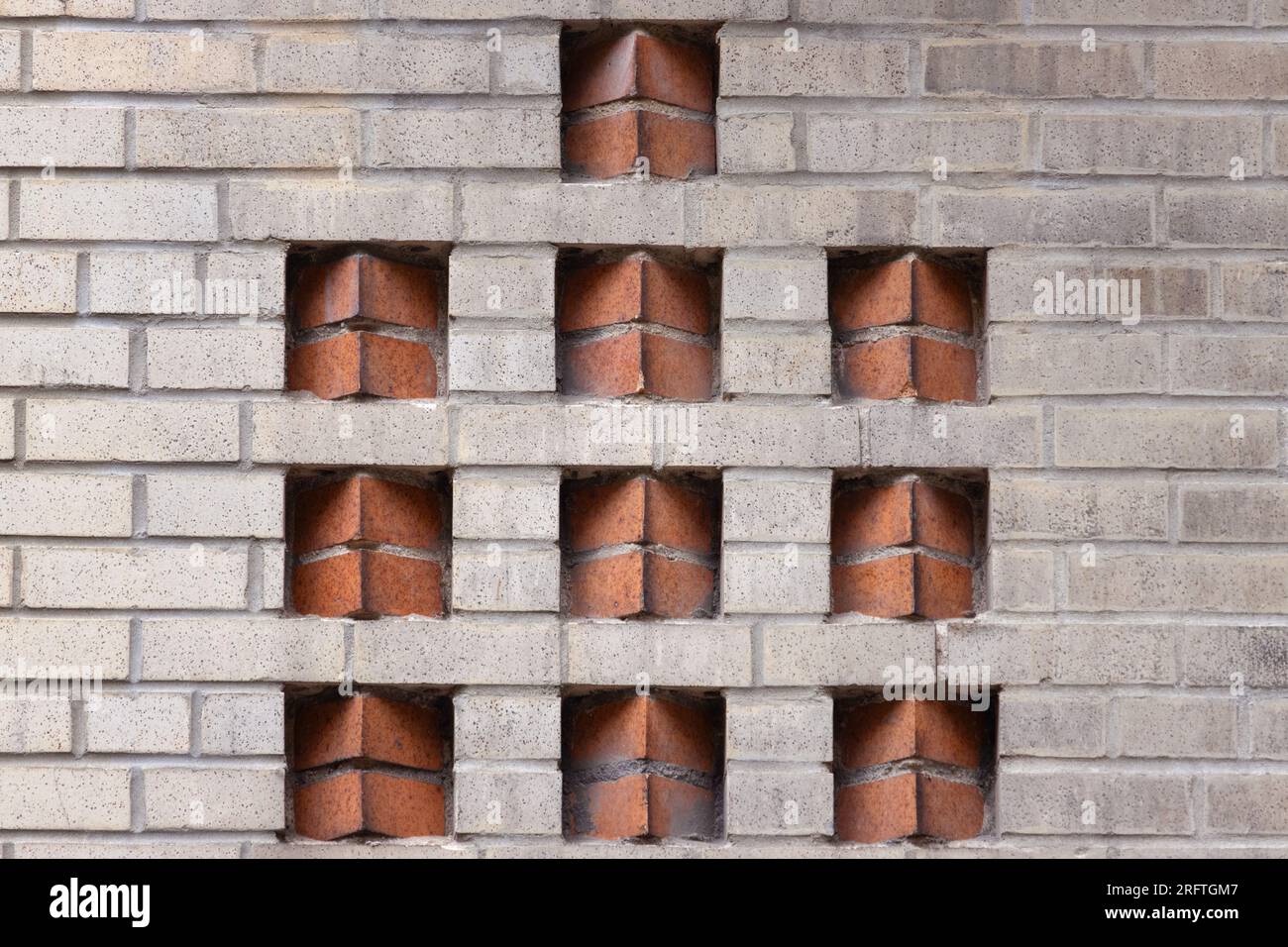 motif de brique décorative art déco à deux tons dans un mur de briques beiges avec des inserts de briques de couleur terre cuite dans un placement en dents de scie créent une géométrie Banque D'Images