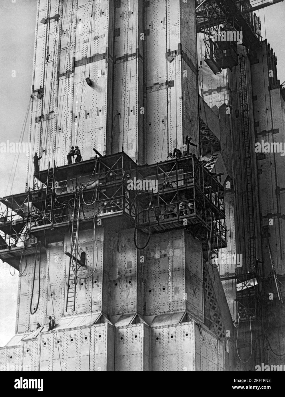 San Francisco, Californie : 1935 le Golden Gate Bridge est en construction avec des riveters au travail dans des cages sur la tour sud. Banque D'Images