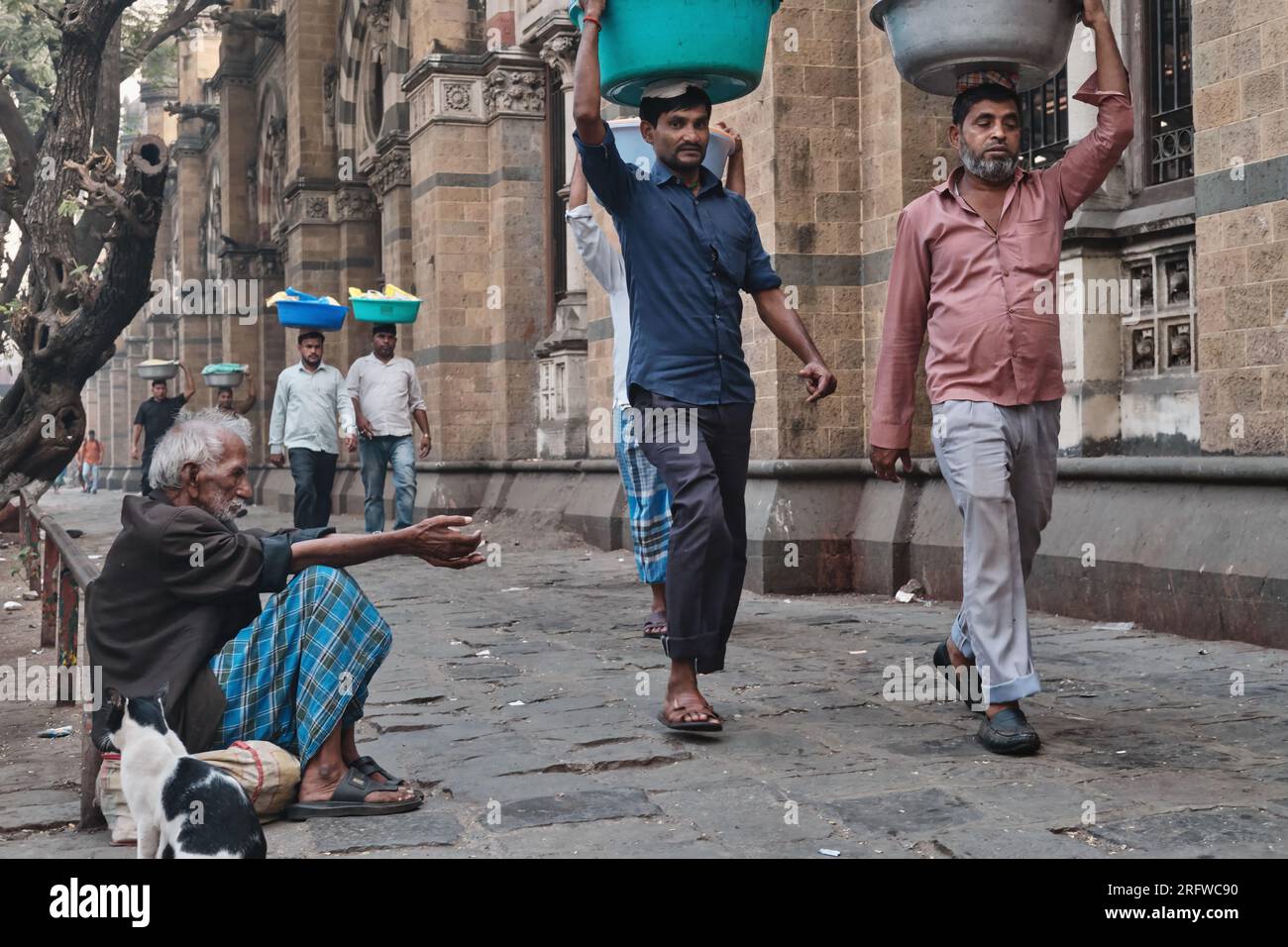 Porteurs avec des plateaux de poissons sur la tête, devant Chhatrapati Shivaji Maharaj Terminus (CMST), à Mumbai, en Inde, pour faire avancer les plateaux en train Banque D'Images