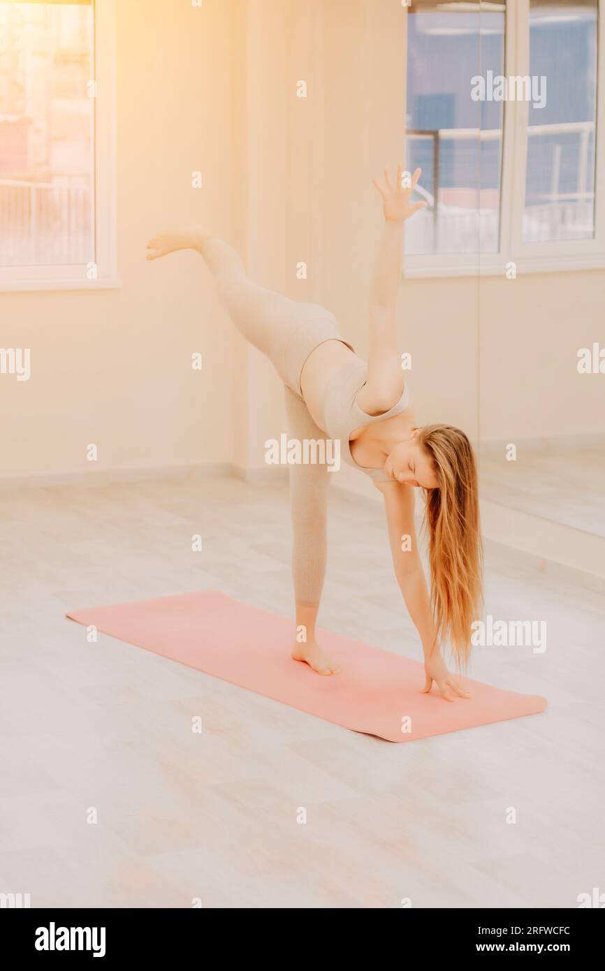 Jeune femme sportive, instructeur de fitness dans les vêtements de sport  faisant des étirements et pilates sur le tapis de yoga dans le studio avec  miroir. Activité physique féminine yoga routine Photo