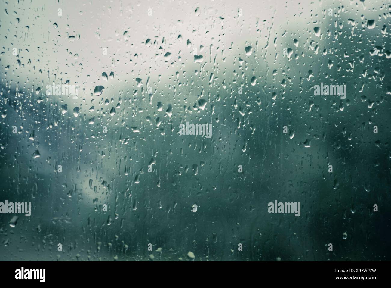 Gouttes de pluie sur une fenêtre avec fond flou indiquant le jour de pluie Banque D'Images