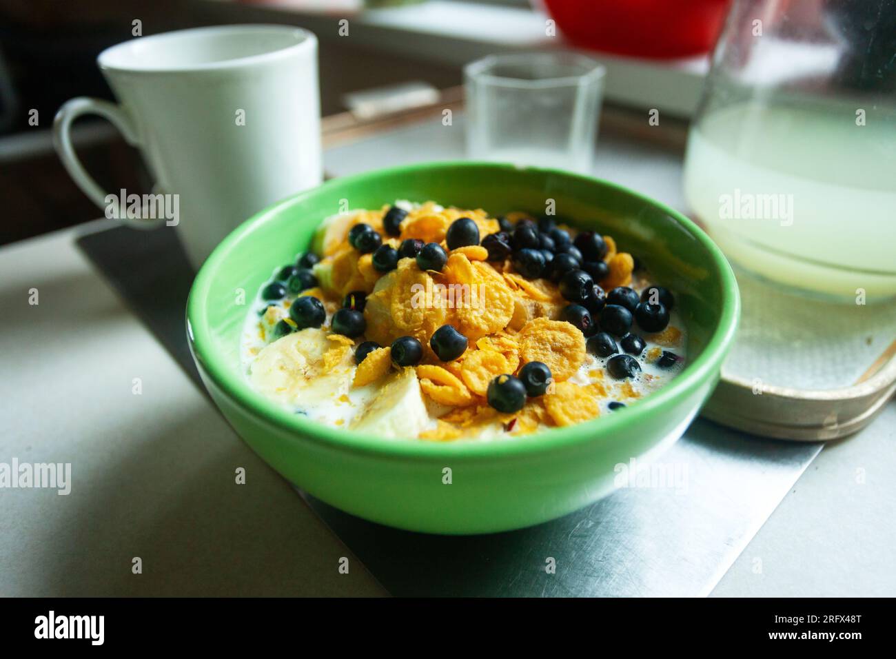 Gros plan d'un bol de cornflakes avec des myrtilles et de la banane dans le lait Banque D'Images