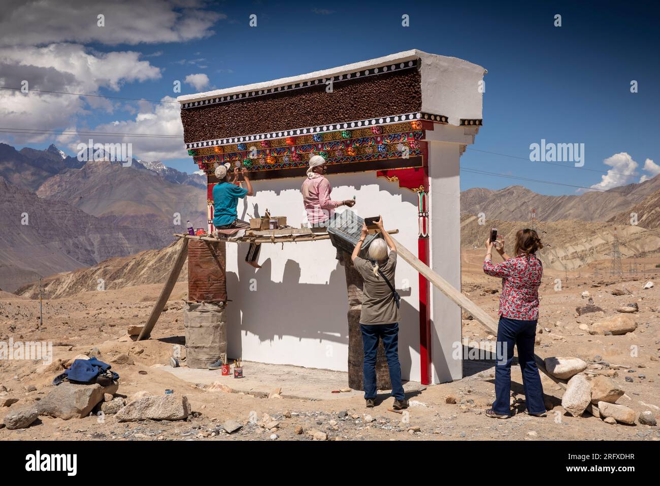 Inde, J&K, Ladakh, touristes photographiant des hommes peignant le mur bouddhiste traditionnel à côté de NH1 Leh à Kargil Highway Banque D'Images