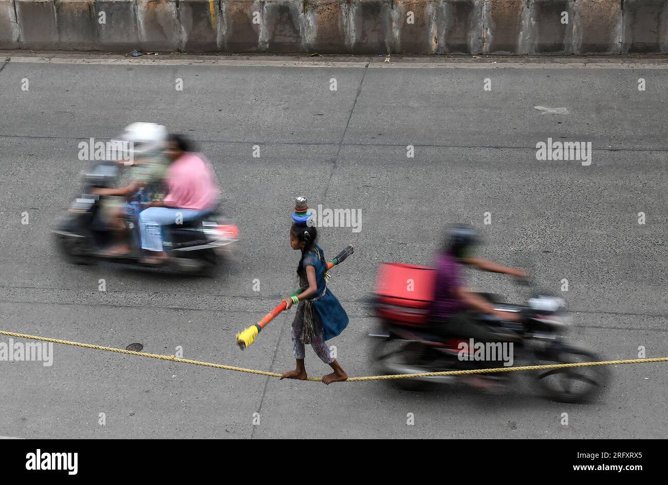 Mumbai, Inde. 06 août 2023. Une fille tenant un bâton de bambou pour s'équilibrer effectue une promenade serrée dans la rue de Mumbai. Les marcheurs à la corde raide gagnent leur vie en se produisant dans les rues en fonction principalement de l'argent donné par les gens qui regardent leur acte risqué. Crédit : SOPA Images Limited/Alamy Live News Banque D'Images