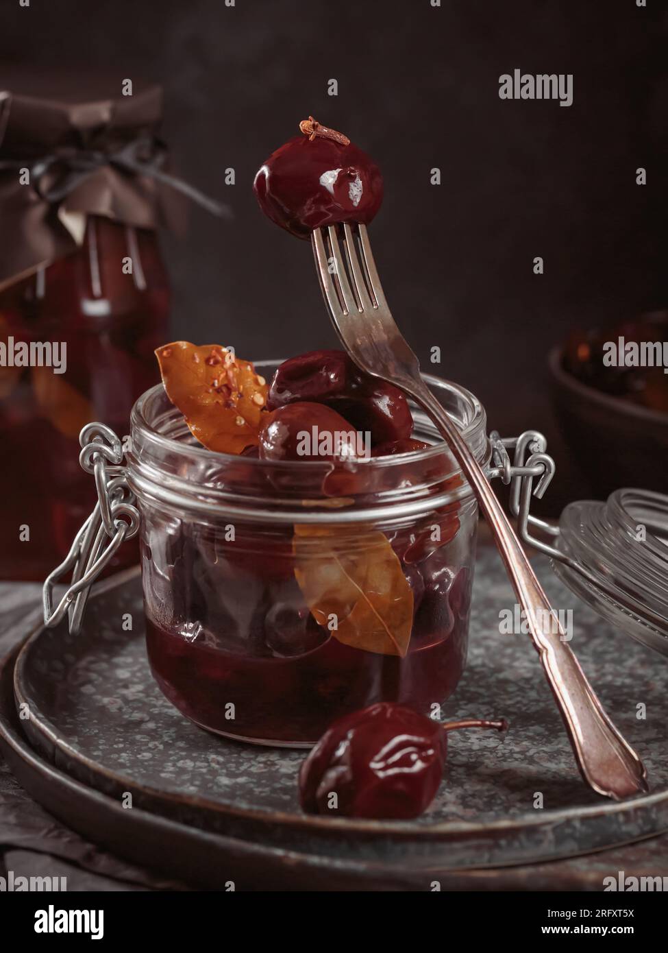 Prunes marinées aux épices dans un pot en verre sur la table de cuisine Banque D'Images