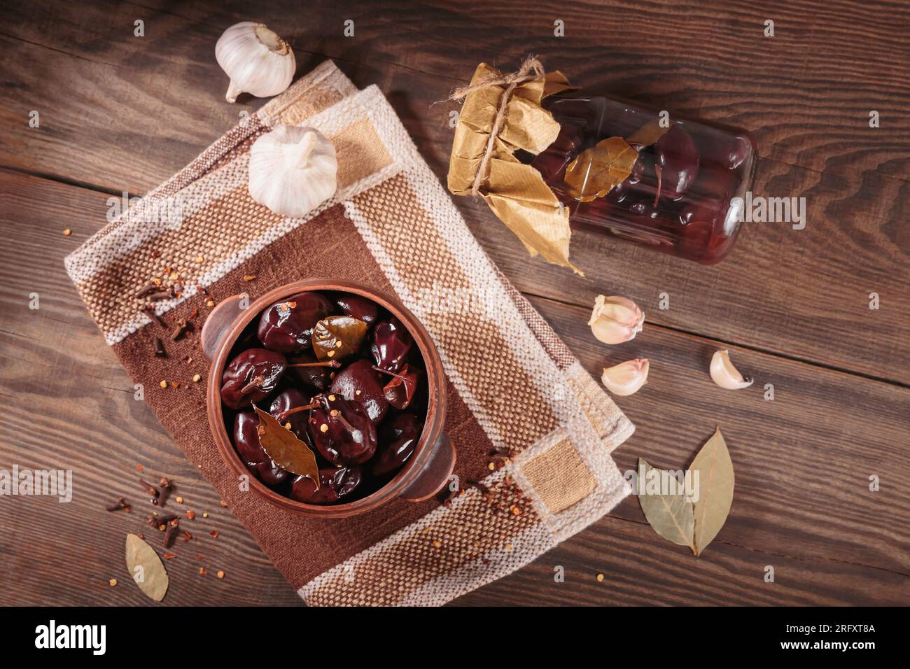 Prunes marinées aux épices dans un pot en verre sur la table de cuisine Banque D'Images