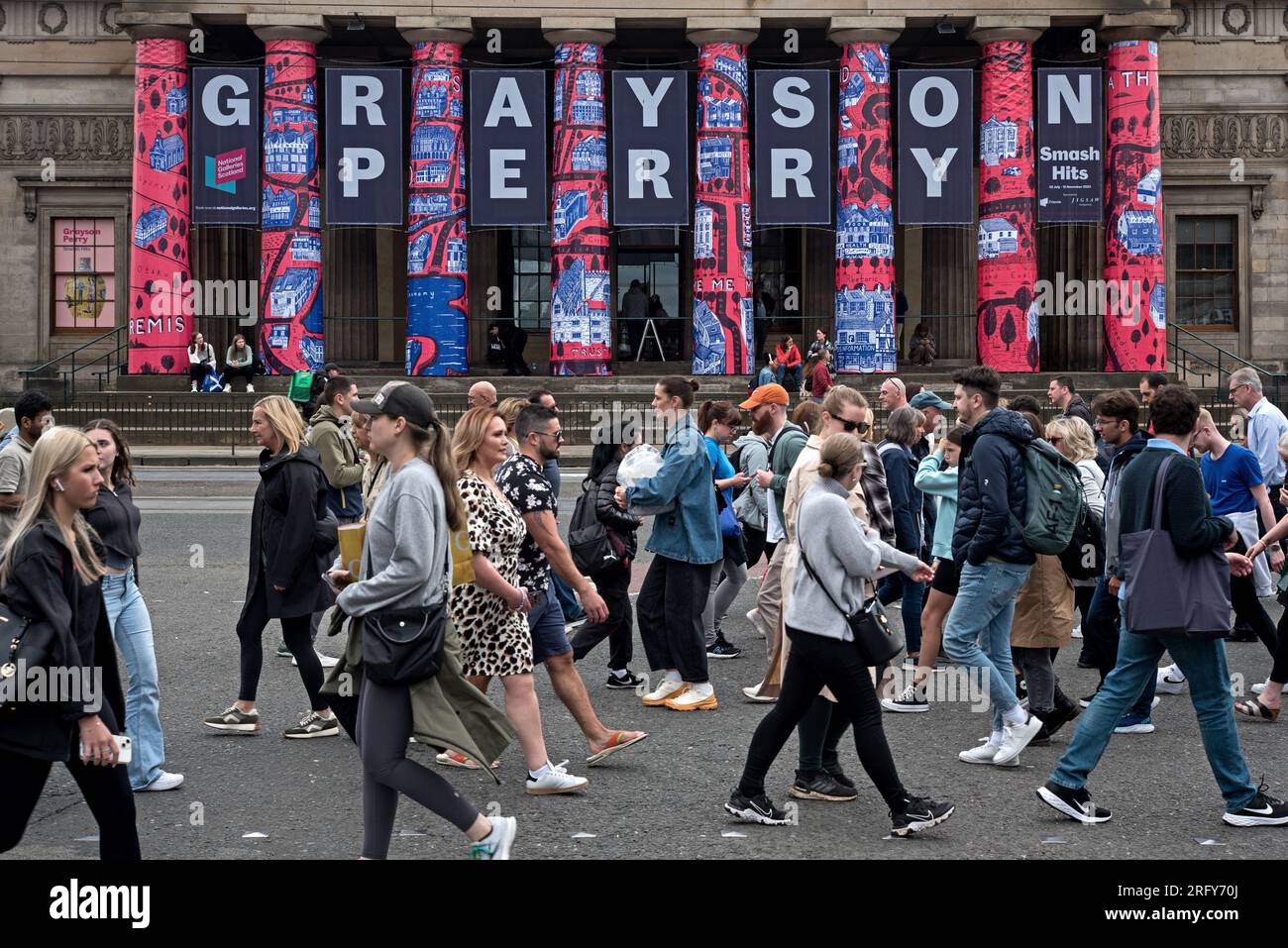 Piétons sur Princes Street se promènent devant la Royal Scottish Academy pour annoncer l'exposition Grayson Perry, qui fait partie du Festival d'Édimbourg 2023. Banque D'Images