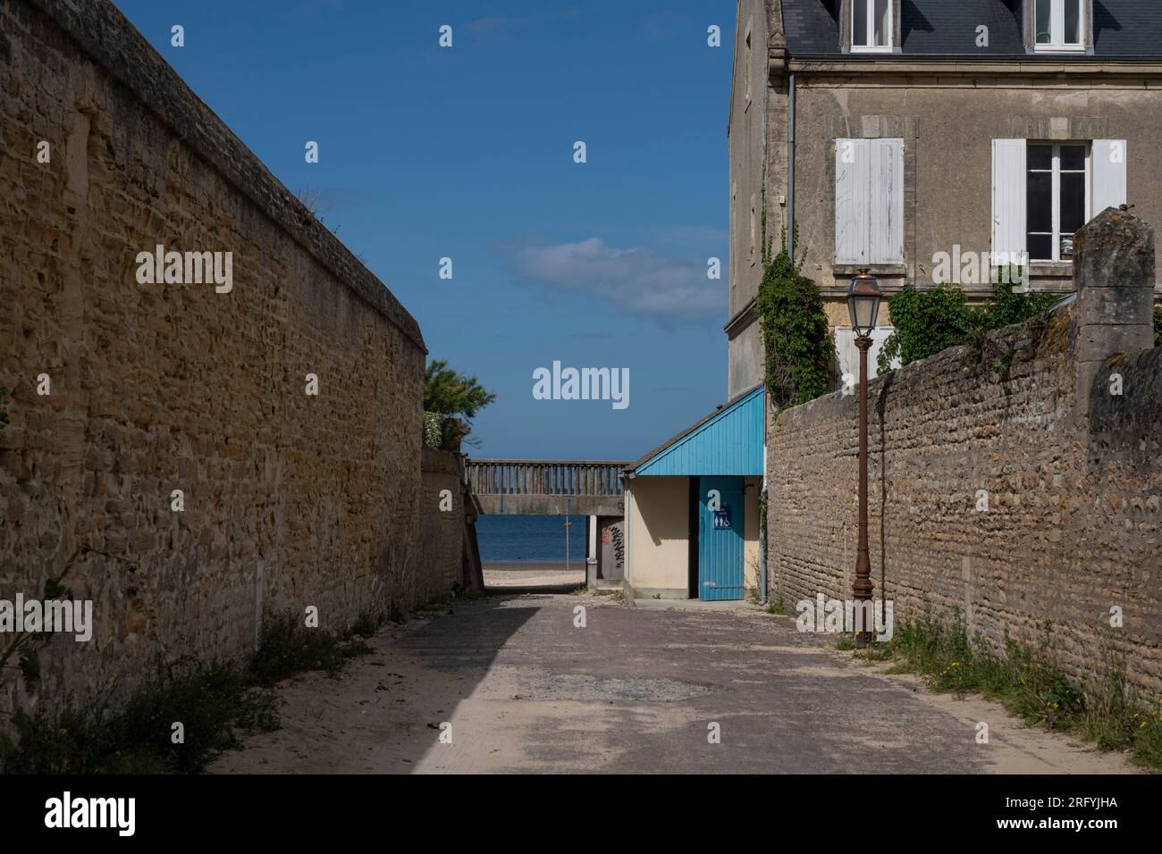 Saint-Aubin-sur-Mer, France - 07 19 2023 : vue sur un étroit passage avec des maisons en pierre reliant la jetée et la plage Banque D'Images