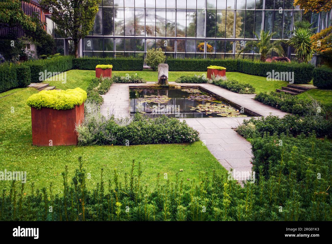 Awe Peat mousse dans des boîtes en acier de vieillissement (COR-TEN) (plusieurs) et étang dans cenrtre avec des nénuphars dans le jardin botanique d'Augsbourg, Bavière Banque D'Images