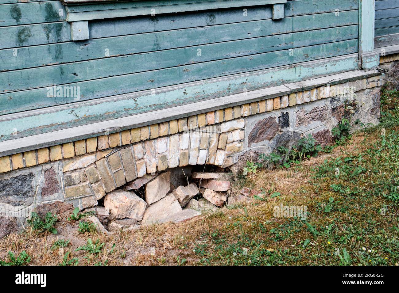 La fenêtre du sous-sol d'une vieille maison en pierre et brique remplie de pierres. Banque D'Images