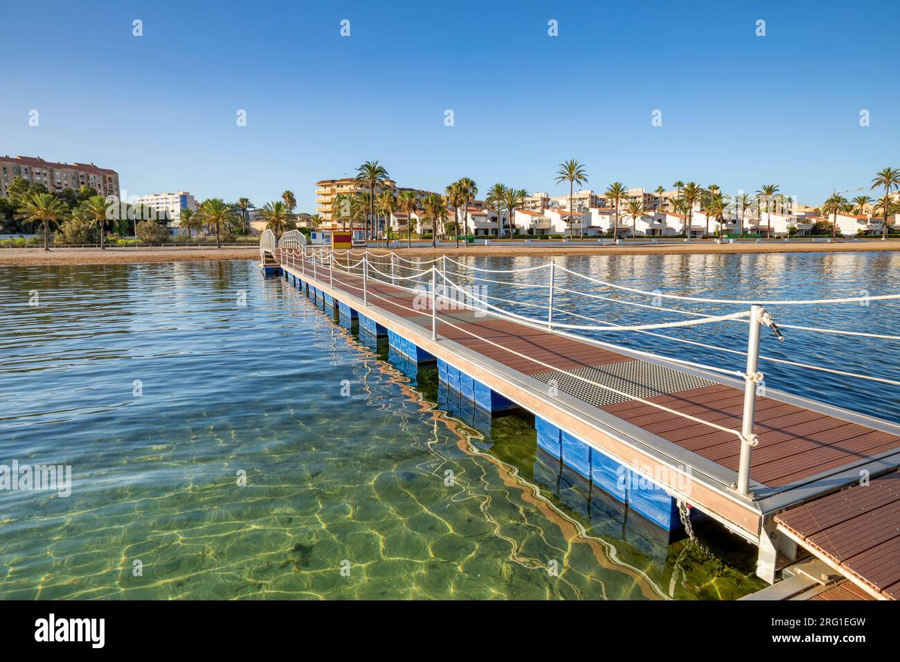 Pont de fer et passerelle en bois sur la plage cristalline d'El Mar de Cristal, dans la Mar Menor, Carthagène, Espagne avec la ville en arrière-plan Banque D'Images