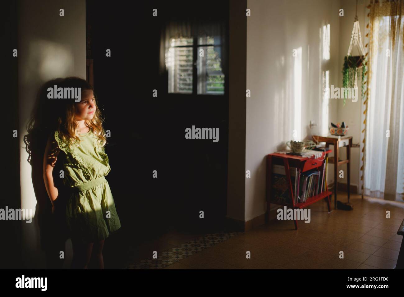 Une fille couchée sur un mur à l'intérieur de sa maison regardant le coucher du soleil Banque D'Images