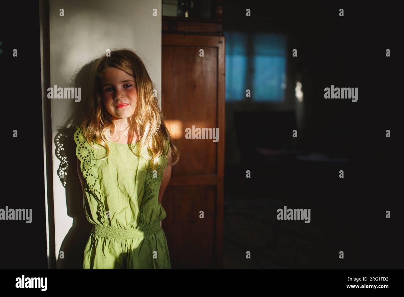 Une fille couchée sur un mur à l'intérieur de sa maison regardant le coucher du soleil Banque D'Images