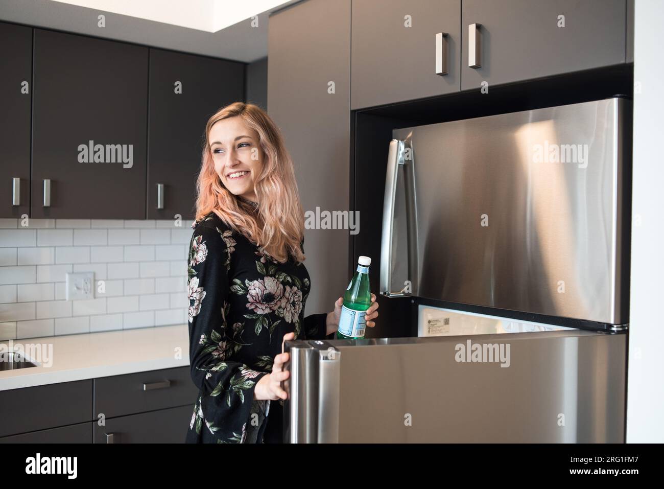 Femme heureuse attrapant boisson hors du réfrigérateur Banque D'Images