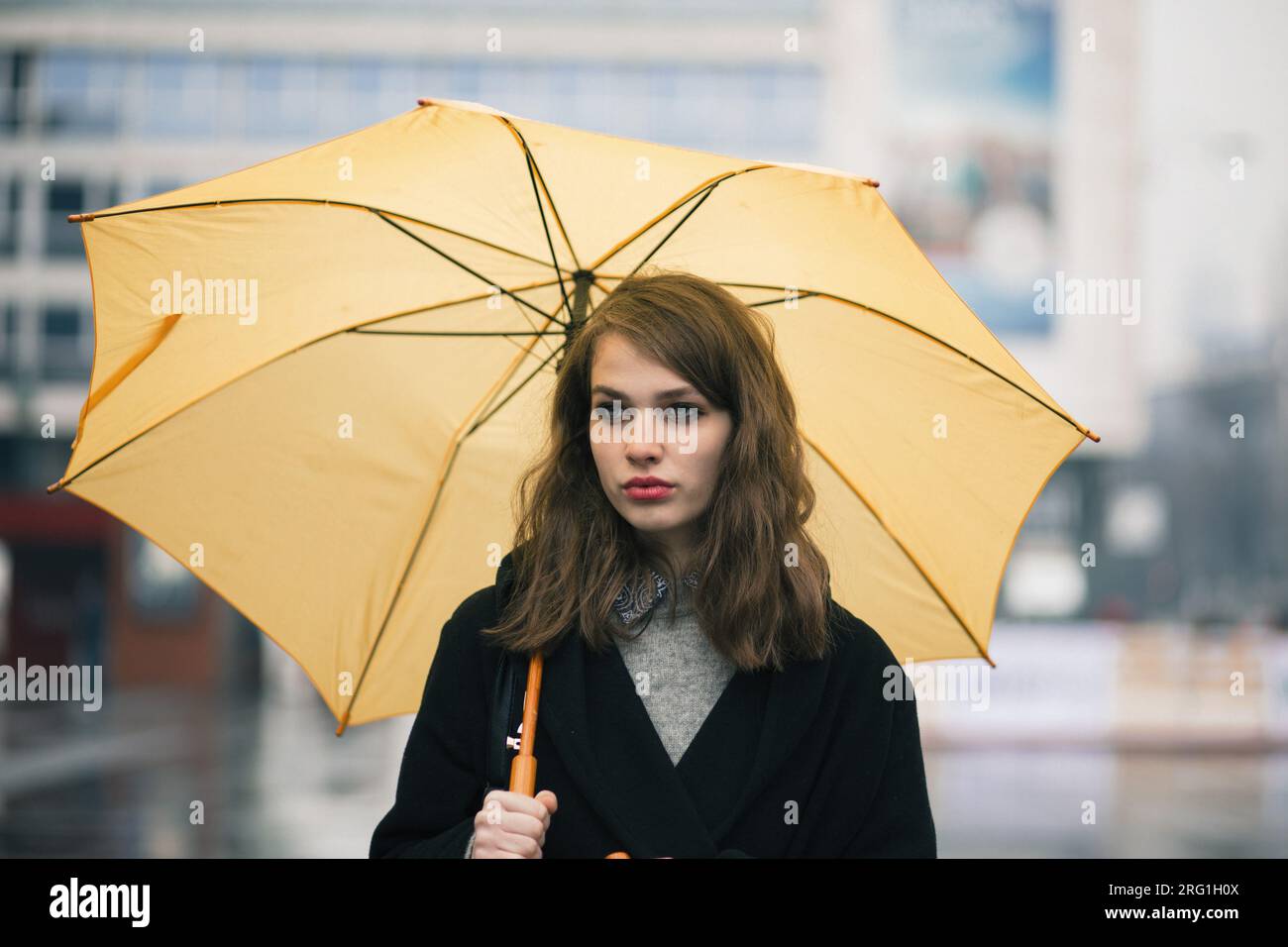 Portrait d'une jeune femme tenant un parapluie jaune Banque D'Images