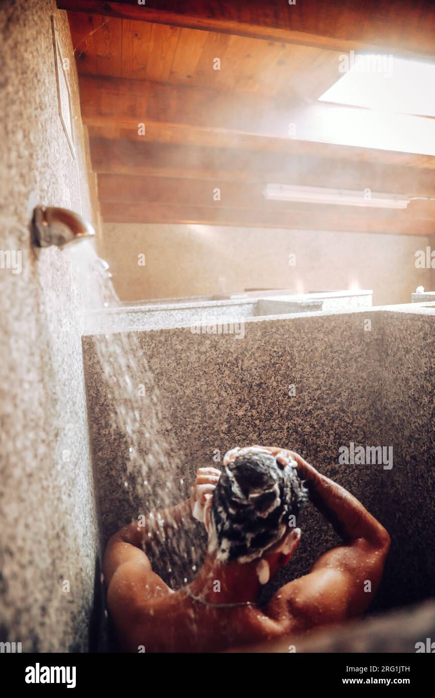 Garçon avec sa douche arrière dans une douche de camping. Lumière naturelle Banque D'Images