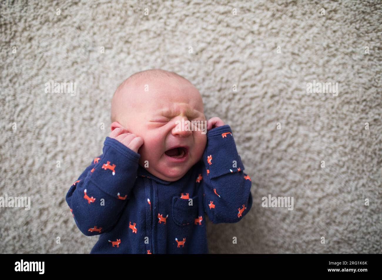 Vue de dessus du bébé nouveau-né pleurant sur le sol Banque D'Images
