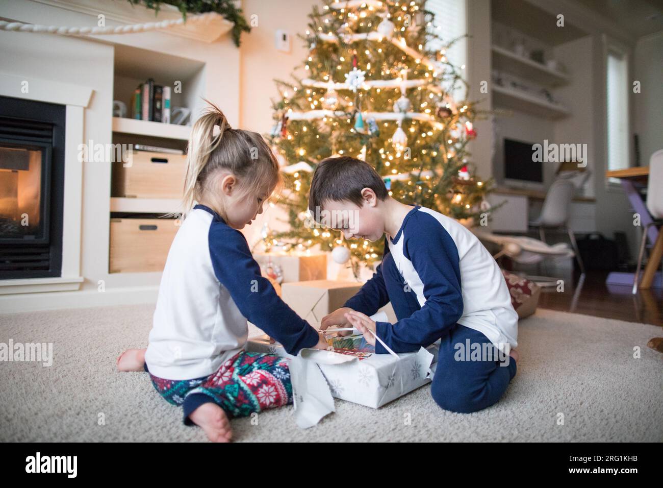 frère et sœur travaillent ensemble pour déballer les cadeaux de noël Banque D'Images