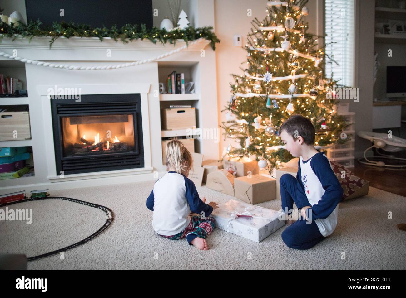 Garçon et fille ouvrant des cadeaux ensemble sous le sapin de Noël Banque D'Images