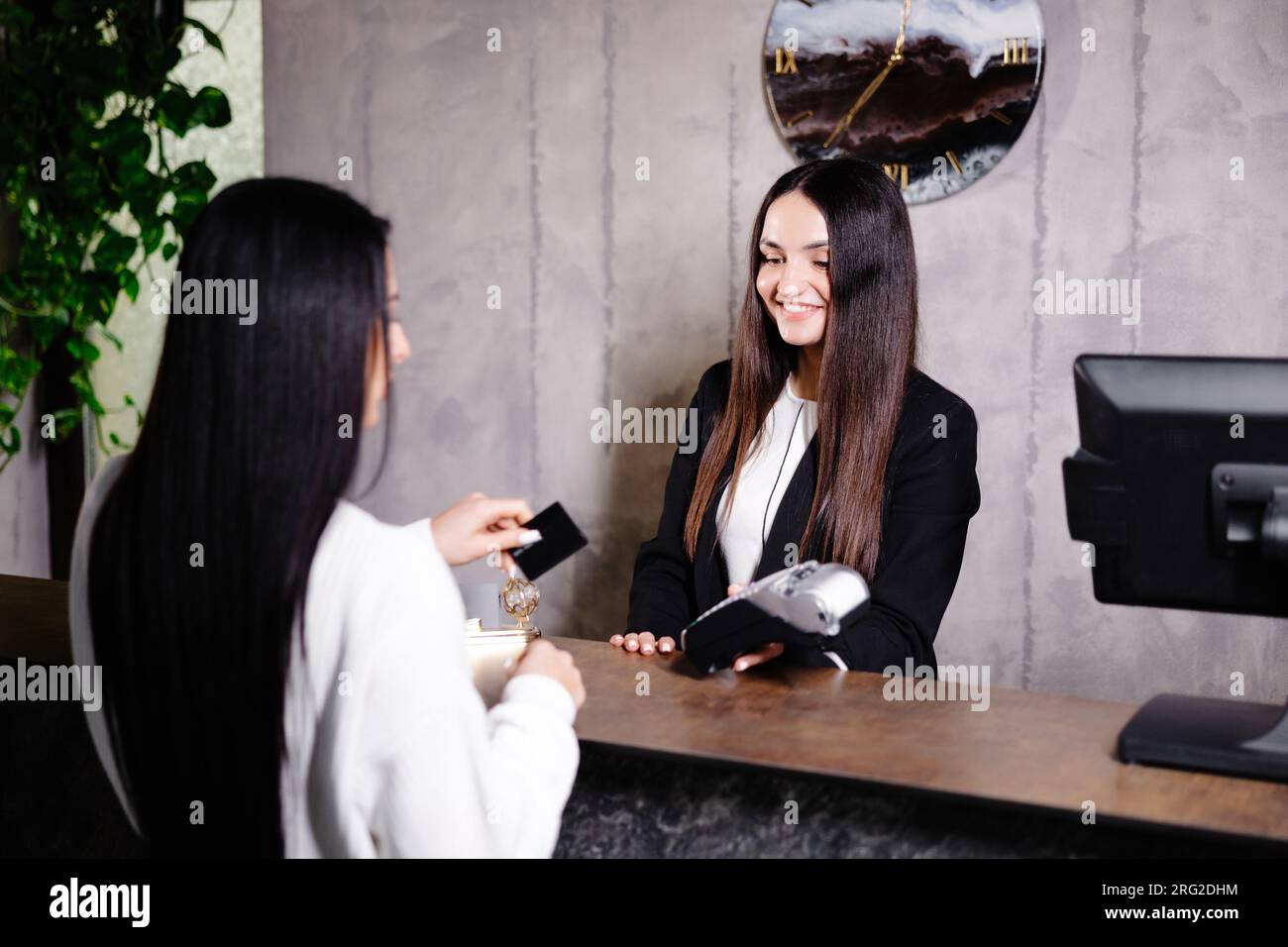 Femme touchant la carte de crédit au terminal du lecteur de carte pour payer les services de l'hôtel. Banque D'Images