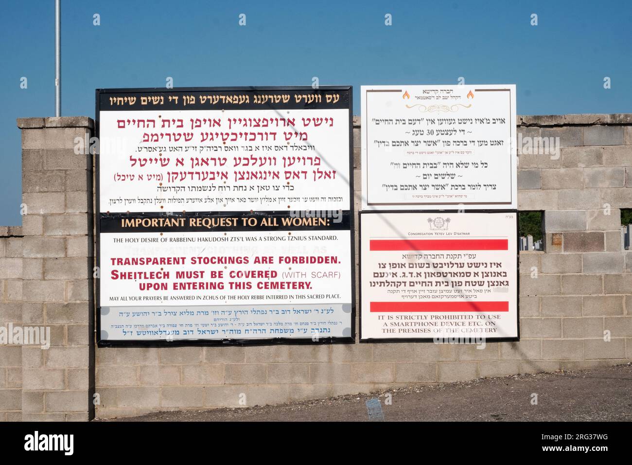 Yiddish, Hebrew & Englssh signes à l'extérieur du vieux Satmar Cemememtery à Kiryas Joel rappelant aux gens quand dire une bénédiction et des règles d'habillage modestes. Banque D'Images