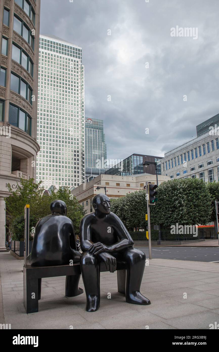 Two Men on a Bench de Giles Penny est une grande œuvre en bronze qui a un air contemplatif au quai de Cabot Square Canary Banque D'Images