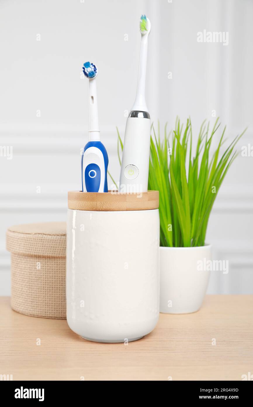 Brosses à dents électriques dans le support sur la table en bois Banque D'Images