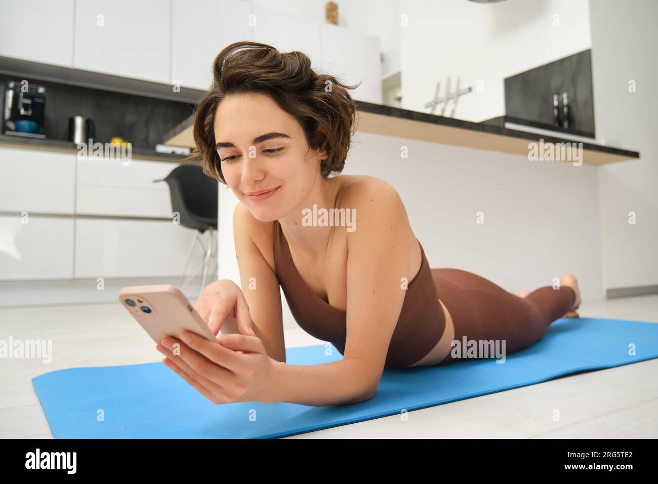 Portrait de femme de fitness couchée sur le tapis de yoga, regardant le  smartphone, en utilisant le téléphone portable pendant l'entraînement Photo  Stock - Alamy