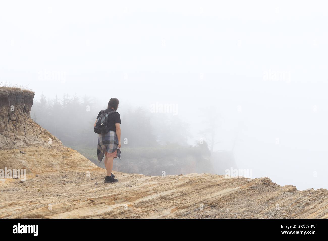 Un homme debout sur le bord d'une falaise au parc national de Shore Acres à Coos Bay, Oregon. Banque D'Images