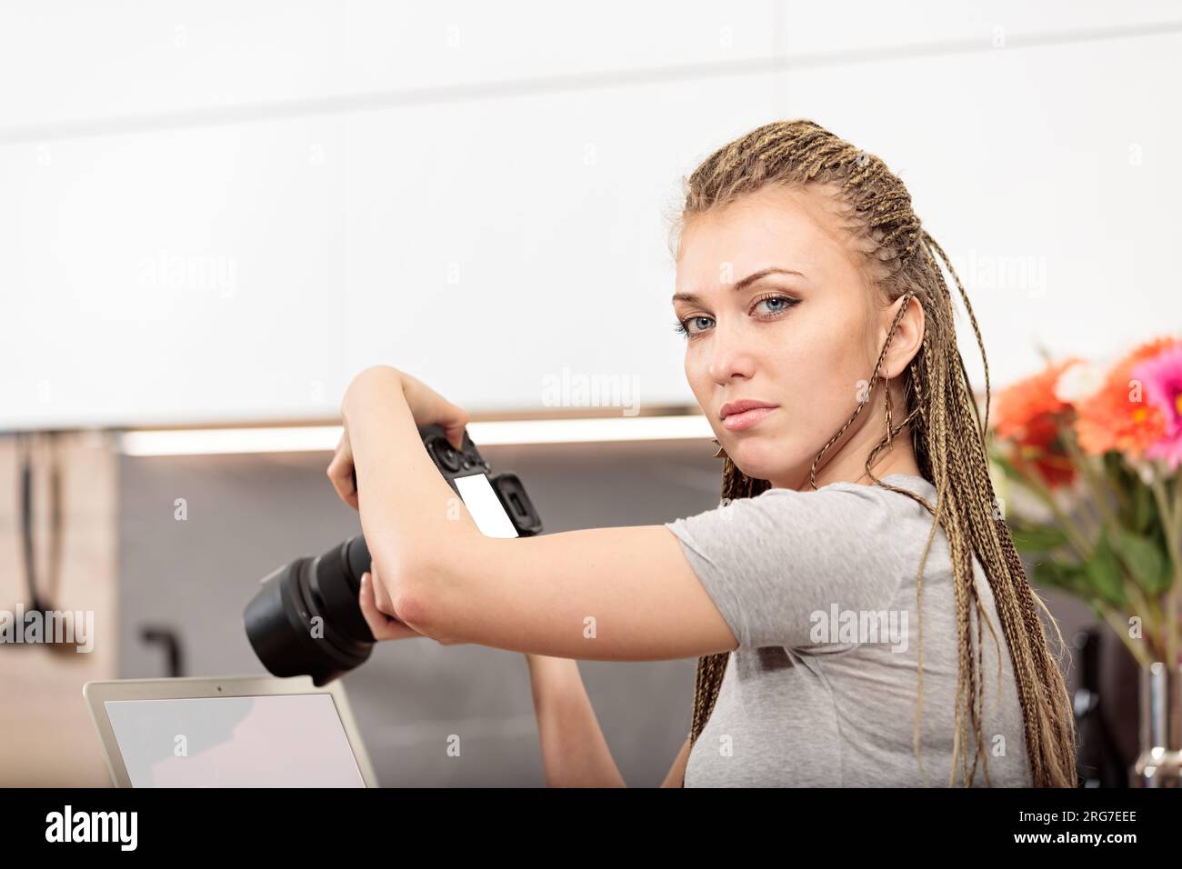 Dans la cuisine, une femme aux cheveux en forme de boîte teste son reflex numérique et son ordinateur portable pour se préparer à la photographie artistique et à la créativité Banque D'Images