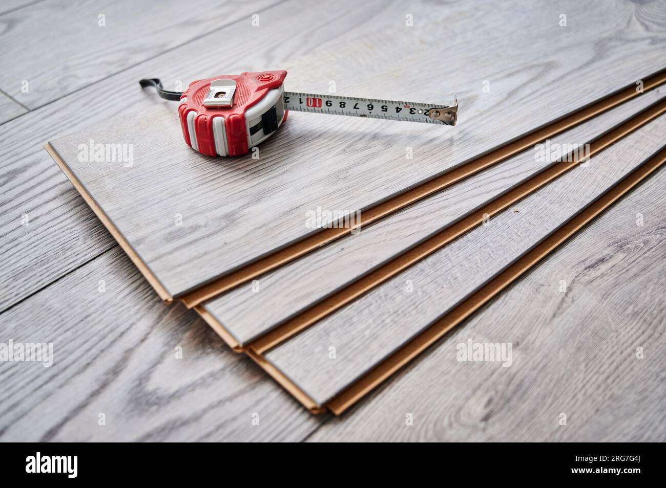 Ruban à mesurer sur des planches de parquet pour la rénovation domiciliaire, les travaux de construction et le design intérieur. Ruban à mesurer en métal sur des échantillons de panneaux stratifiés avec motif et texture en bois pour le revêtement de sol. Banque D'Images