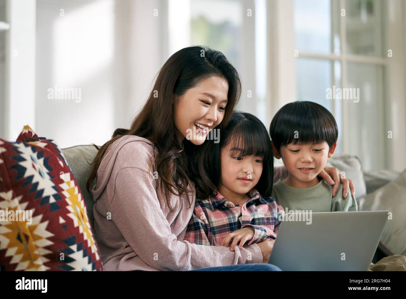 jeune mère asiatique et deux enfants assis sur le canapé de la famille à la maison regardant un film ensemble à l'aide d'un ordinateur portable Banque D'Images