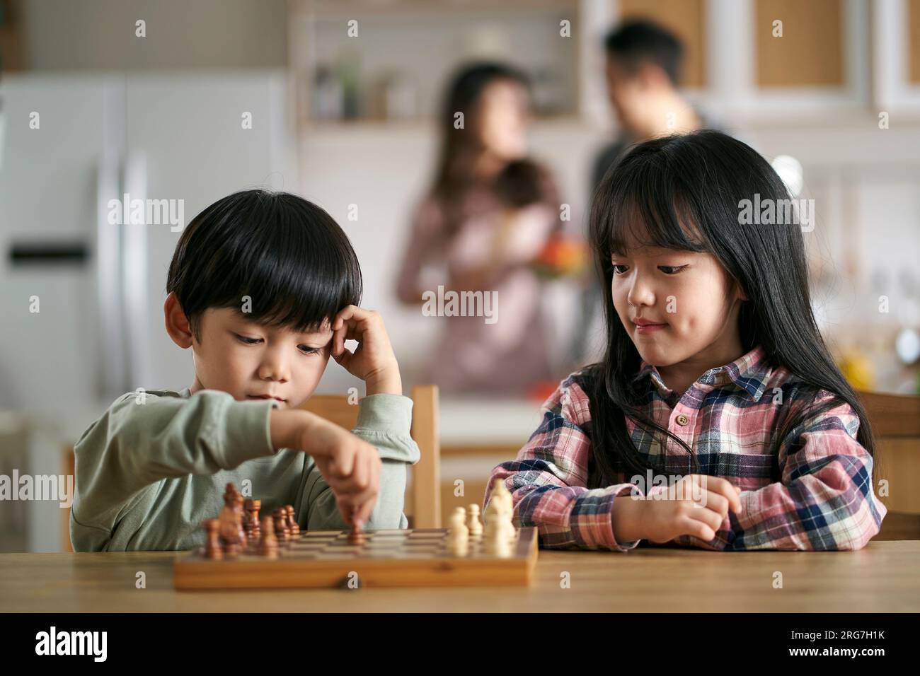 deux enfants asiatiques frère et sœur assis à table à la maison jouant aux échecs Banque D'Images